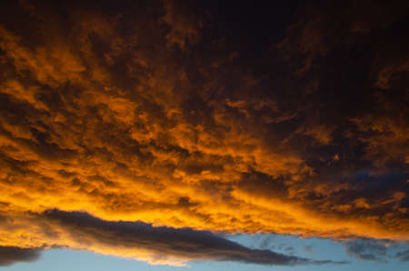 Lush, heavy clouds, painted orange by the sun at sunset. Texture.の写真素材