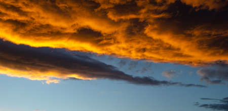 Lush, heavy clouds, painted orange by the sun at sunset. Texture.の写真素材