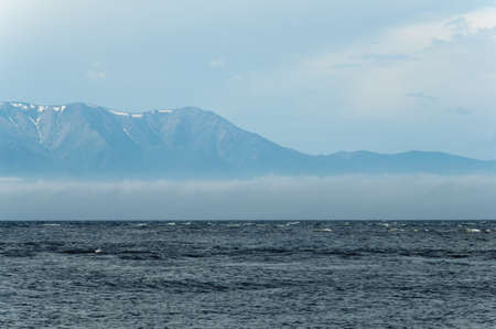 View of the surface of the lake from the shore. Small waves, fog in the distance.の写真素材
