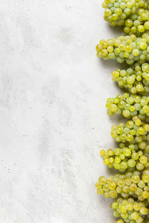 Large ripe green grapes. Ripe juicy grapes with vine foliage on a light gray concrete background with copy space from above. for designの写真素材