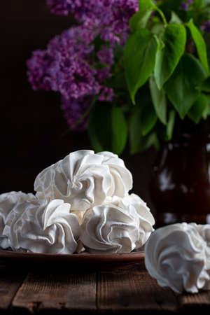 apple marshmallow on a wooden background in a plate, in the background - a cup of coffee, lilac branches.の写真素材