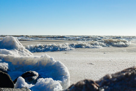 Close-up of the icy seashore, frozen waves, rocks and sun glare on the iceの写真素材