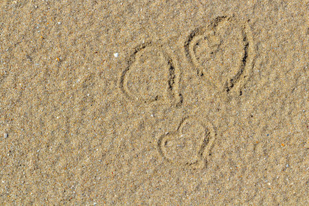 Heart drawn in the sand. beach background. top view. declaration of love through a pictureの写真素材