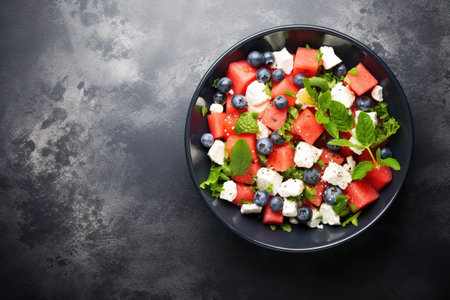 Summer salad with watermelon, blueberries and feta cheese, above view on a dark stone backgroundの素材