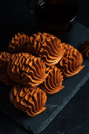 Coffee Zephyr features beautifully crafted chocolate confections on a dark slate surface, paired with a cup of coffee, evoking a warm and inviting ambiance for dessert enjoymentの写真素材