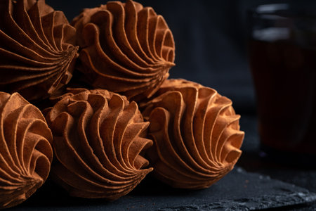 Coffee Zephyr dessert features beautiful swirls, placed on a dark slate surface, alongside a glass of dark beverage, enhancing the rich visual appealの写真素材