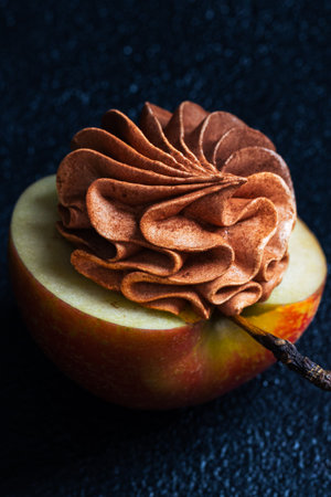 A vibrant red apple features a beautifully crafted chocolate frosting on top, merging fresh fruit with dessert artistry, creating an enticing visual treatの写真素材