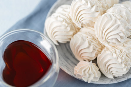 Meringue cookies beautifully arranged on a plate, with a glass of tea and decorative spices nearby, creating a warm and inviting dessert atmosphereの写真素材
