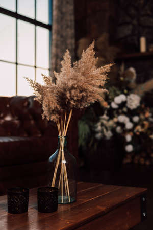 Vase with dried flowers stands on a wooden table in the interior. High quality photoの写真素材