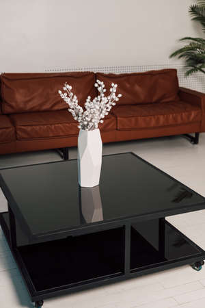 On a black glass table is a white vase of flowers in the officeの写真素材
