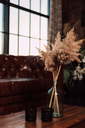 Vase with dried flowers stands on a wooden table in the interiorの写真素材