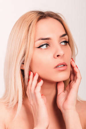 Young beautiful blonde touches her hands to her faceの写真素材