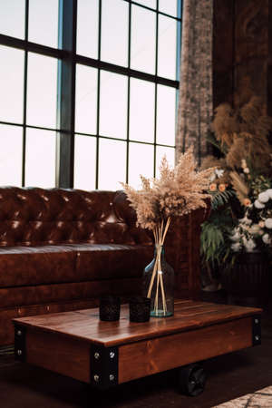 Vase with dried flowers stands on a wooden table in the interiorの写真素材
