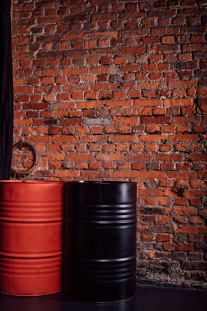 Two barrels of red and black stand against the background of a brick wallの写真素材