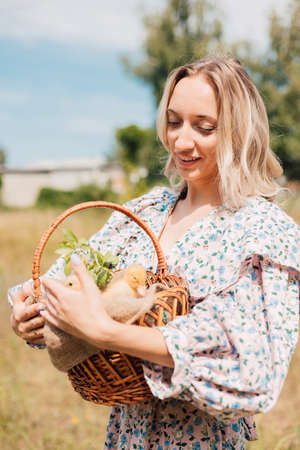 A young beautiful girl holds a basket with ducklings in her handsの写真素材