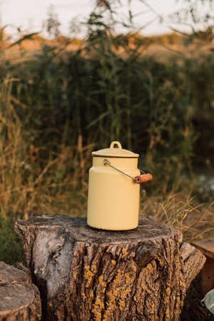 Yellow metal milk container stands on a stump in the villageの写真素材