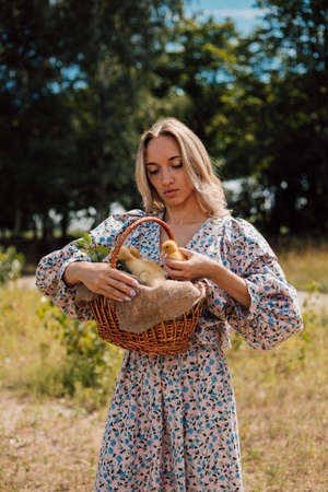 A young woman in long dress holds a basket of ducklings and smilesの写真素材