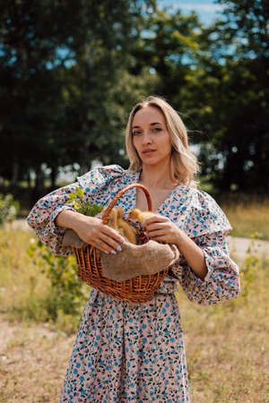 A young woman in long dress holds a basket of ducklings and smilesの写真素材