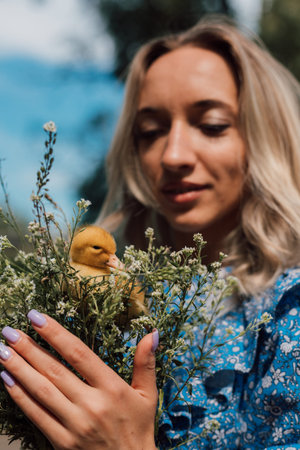 Beautiful girl holding wildflowers and duckling in her hands