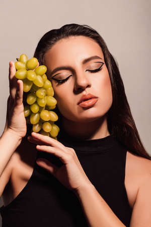 Beautiful young girl with a bunch of green grapesの素材 [FY310189452110]