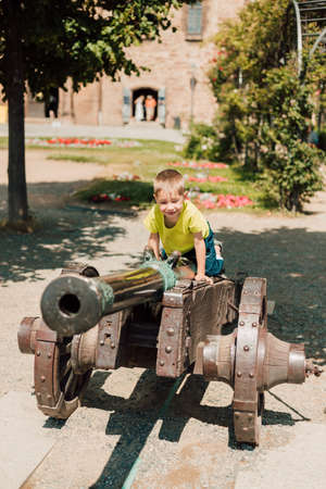 A little boy sits on top of a historic cannonの写真素材