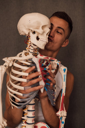 A man holds a skeleton leg in his hands and points a finger at itの写真素材