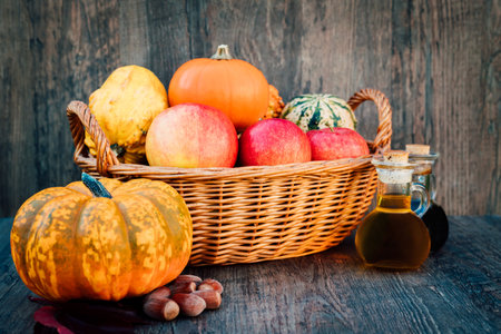 Autumn still life composition of pumpkins apples in a wicker basket on the tableの写真素材