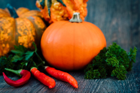 Chili peppers, pumpkins, parsley autumn vegetables on a wooden tableの写真素材
