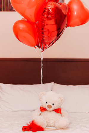 White teddy bear with red heart balls on the couch for Valentines Dayの写真素材