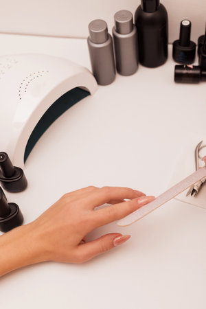 The process of sawing the nail with a nail file. Womens manicure at homeの写真素材