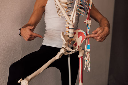 A man in a white T-shirt studies the structure of the human skeletonの写真素材