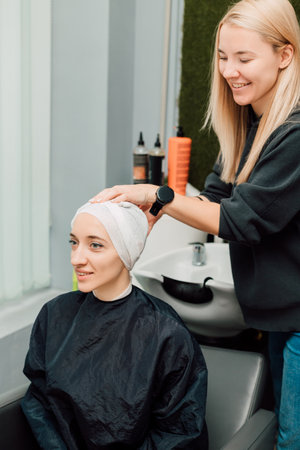 A woman with a towel on head. Hair washing, treatment in the hairdressing salonの写真素材