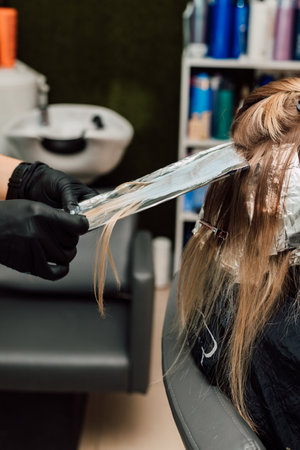 A professional hairdresser applies dye to a clients hair. Hair coloringの写真素材