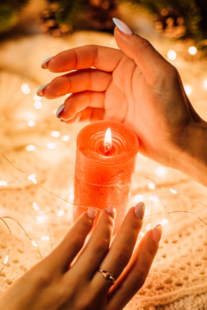 Christmas composition. Womens hands near a red candleの写真素材