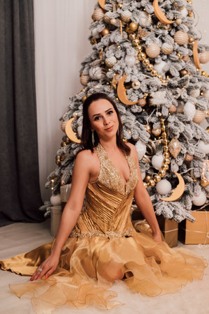 Young beautiful girl in a long dress near the Christmas treeの写真素材