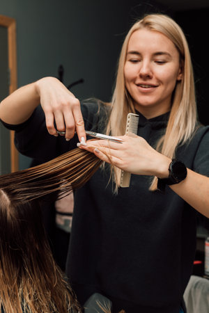 A hairdresser cuts a blondes hair in a beauty salon. Womens haircutの写真素材