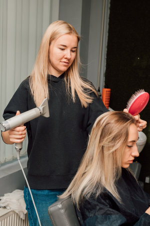 A hairdresser dries clients hair in salon. Hairdressers hands with hair dryerの写真素材