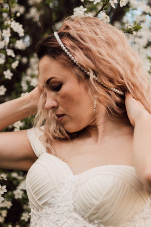 Beautiful blonde next to cherry blossoms in the garden. Spring floweringの写真素材