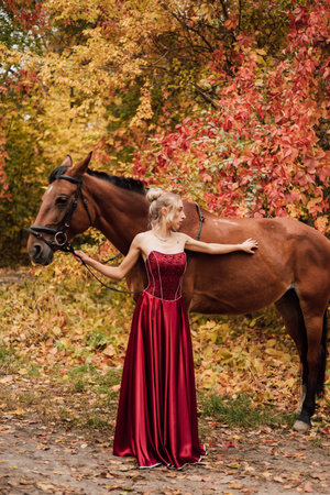 Female portrait next to a horse. Horseback riding in the autumn forestの写真素材