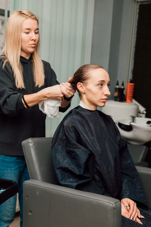 A hairdresser does hair styling for a blonde in a beauty salon. Hair Careの写真素材