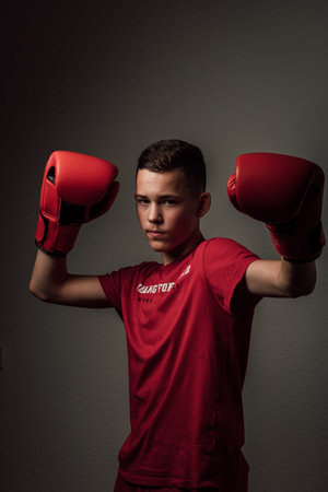 A teenage boxer athlete is training to box on dark background. Aggressive sportの写真素材