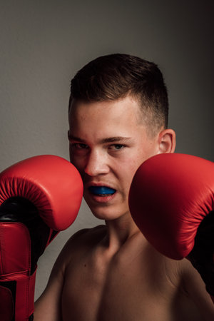 A teenage boxer athlete is training to box on dark background. Aggressive sportの写真素材