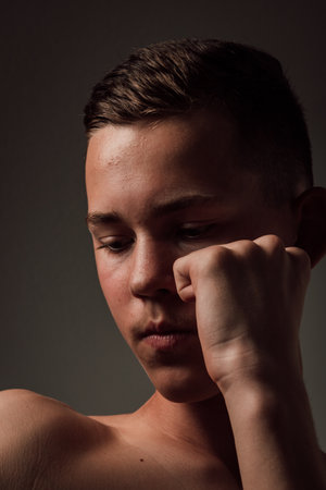 A teenage boxer athlete is training to box on dark background. Aggressive sportの写真素材