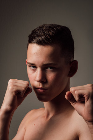 A teenage boxer athlete is training to box on dark background. Aggressive sportの写真素材