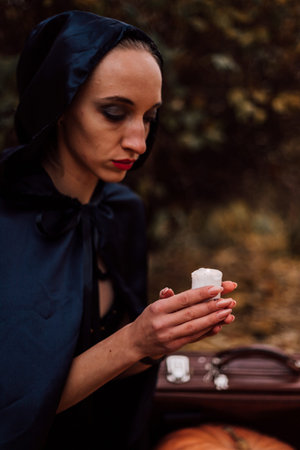 A young witch in the forest makes a spell, reads a book. Magic in the forest. Halloween. High...