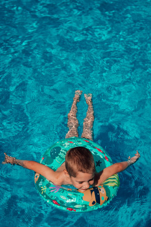 A little boy with a circle bathes in clear blue water. Swimming in the poolの写真素材
