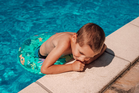 A little boy climbs out of the pool. A child bathes at noon in the heatの写真素材