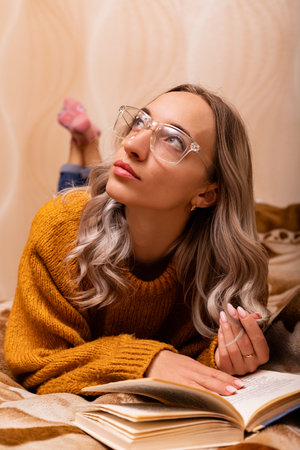 Woman with a book on the sofa. A woman reads a book. Learning at home. High quality photoの写真素材