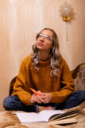 A teacher reads a book at home on the couch. World Knowledge Day. High quality photoの写真素材