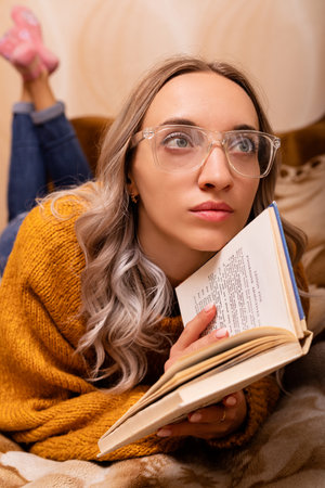 Woman at home on the couch reading a book. Home office. Remote Learning. High quality photoの写真素材